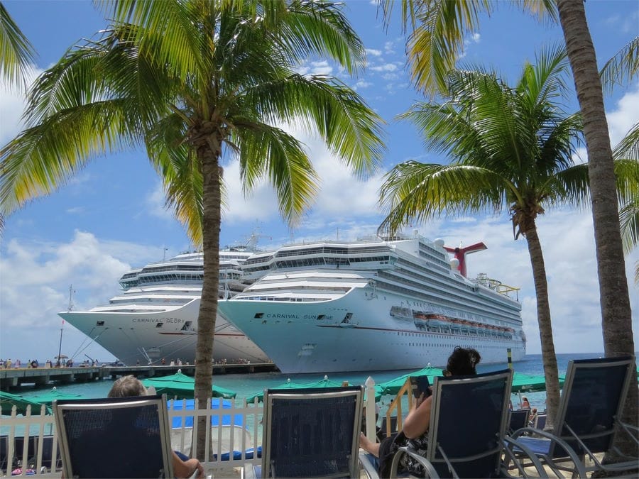 A Carnival cruise ship docked alongside another cruise ship in the Bahamas