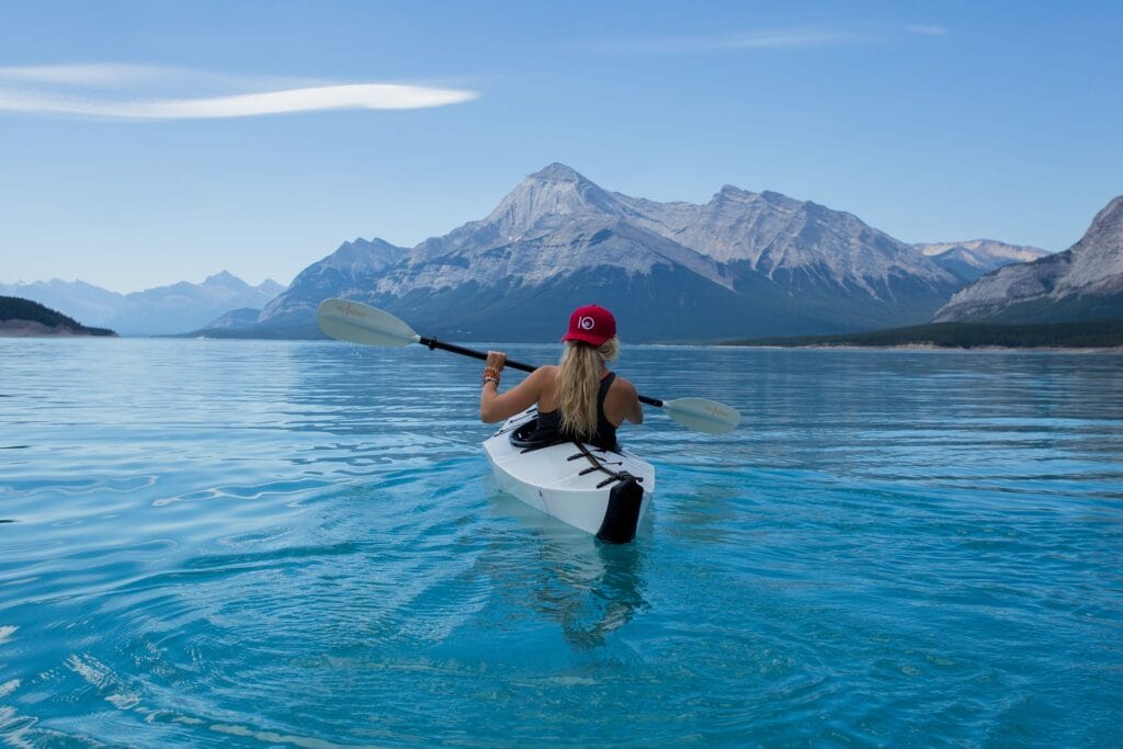 A woman kayaking in the waters surrounded by mountains