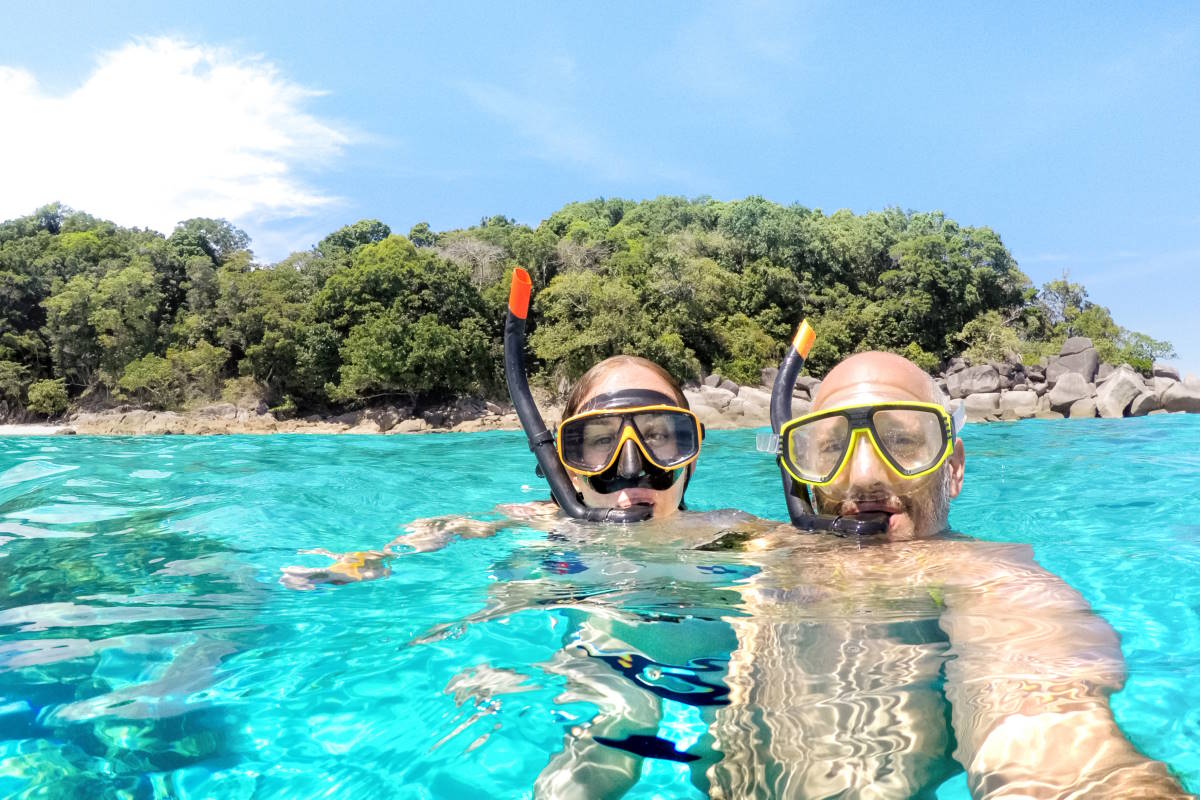 Young couple taking selfie in tropical scenario with waterproof