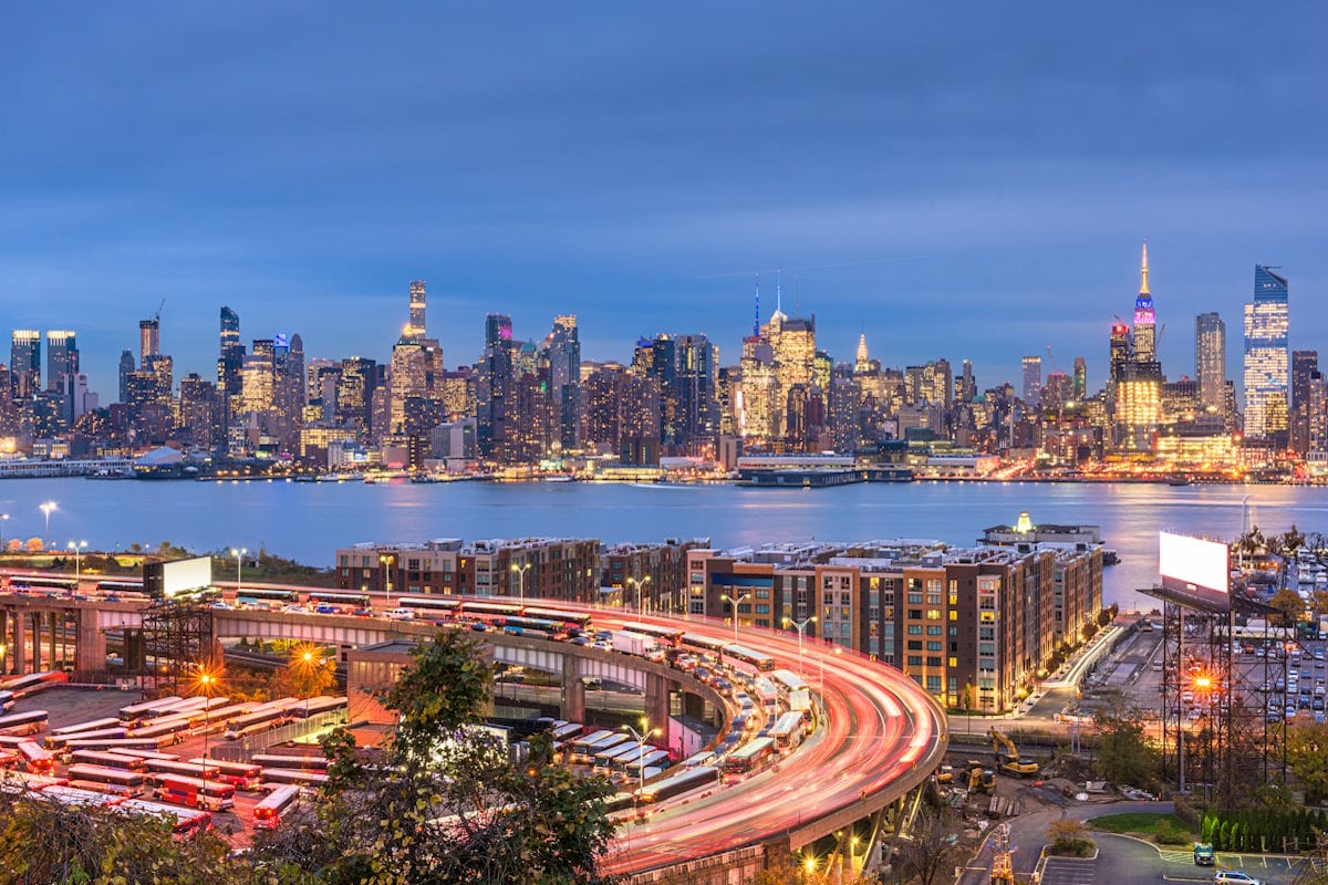 New York, New York, USA cityscape and highways from across the Hudson River at dusk.