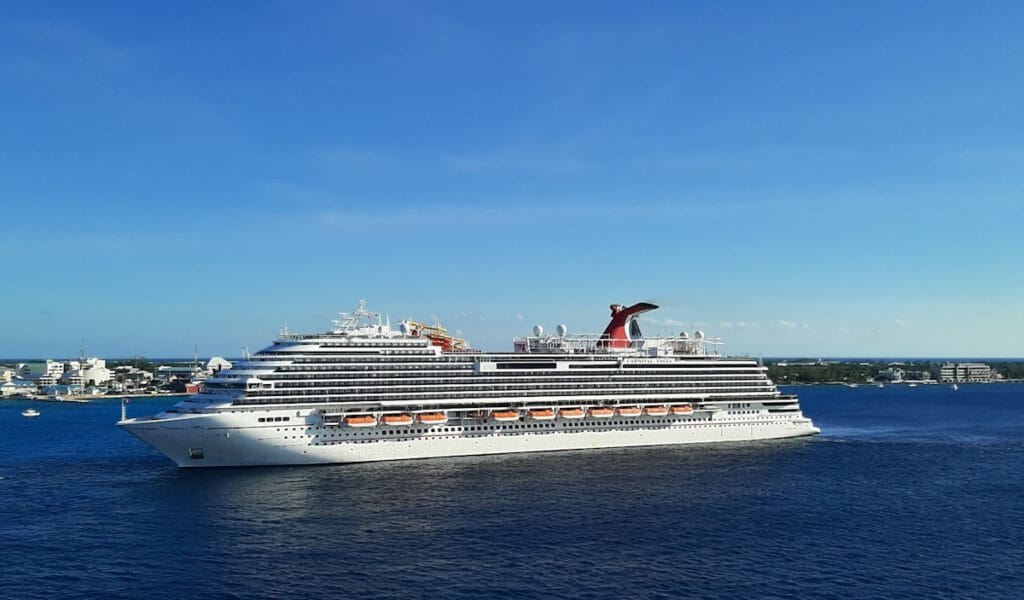 Carnival cruise ship sailing along the shoreline of a city