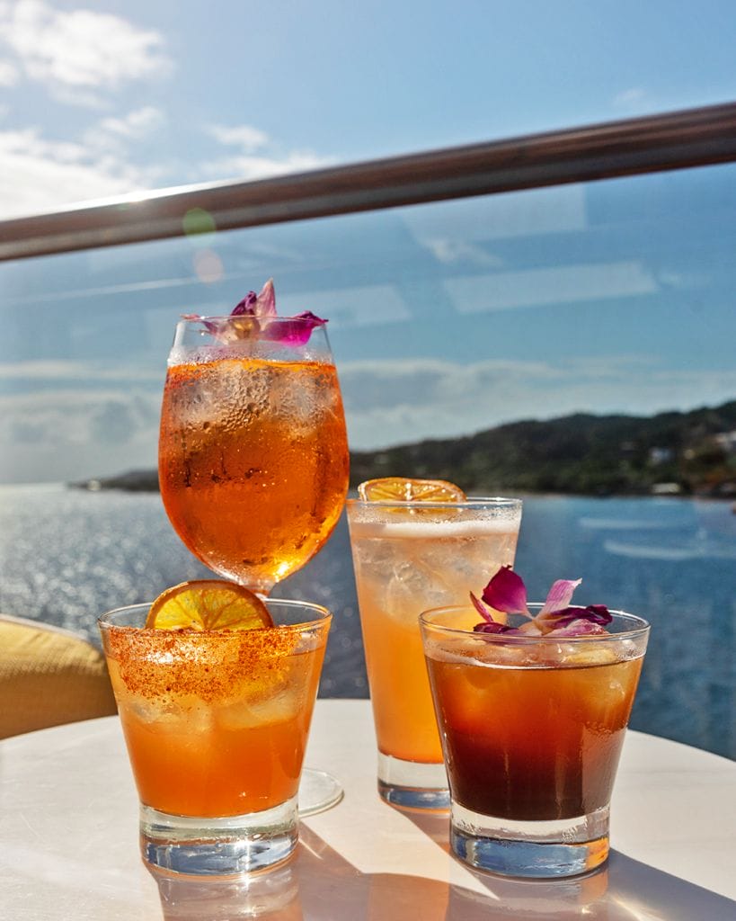 Drinks sitting on a table on a cruise ship deck overlooking the ocean